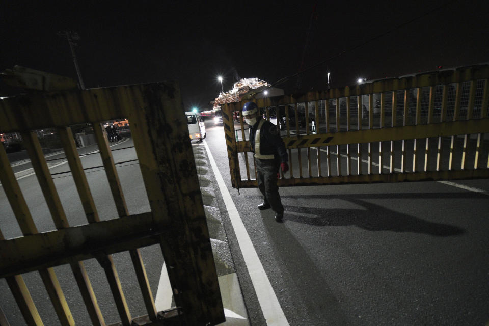 A port security officer closes a gate near the quarantined Diamond Princess cruise ship at a port in Yokohama, near Tokyo, Wednesday, Feb. 19, 2020. Hundreds of passengers began leaving the cruise ship Wednesday after the end of a much-criticized, two-week quarantine that failed to stop the spread of a new virus among passengers and crew. (AP Photo/Eugene Hoshiko)