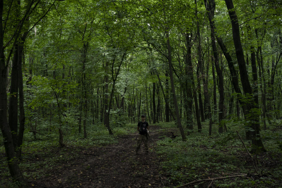 In this July 27, 2018 photo, a member of Sokil (Falcon), the youth wing of the nationalist Svoboda party, stands in a forest as he guides participants to the "Temper of will" summer camp in a village near Ternopil, Ukraine. (AP Photo/Felipe Dana)