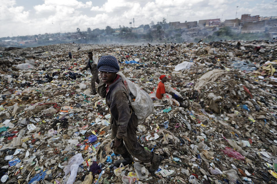 In this photo taken Wednesday, Dec. 5, 2018, a man who scavenges for pieces of plastic for a living walks across a mountain of garbage at the dump in the Dandora slum of Nairobi, Kenya. As the world meets again to tackle the growing threat of climate change, how the continent tackles the growing solid waste produced by its more than 1.2 billion residents, many of them eager consumers in growing economies, is a major question in the fight against climate change. (AP Photo/Ben Curtis)