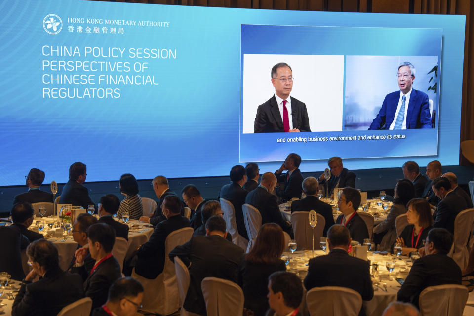 Governor of the People's Bank of China Yi Gang, right, speaks via video during the Global Financial Leaders' Investment Summit in Hong Kong, Wednesday, Nov. 2, 2022. Chinese regulators downplayed China's real estate slump and slowing economic growth while Hong Kong's top leader pitched Hong Kong as a unique link to the rest of China at a high-profile investment summit Wednesday. (AP Photo/Bertha Wang)