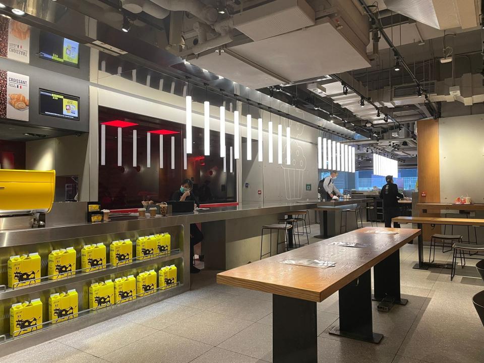 Industrial-style counter with hanging cylindrical lighting and tile floor in a restaurant. A wooden-top table with gray, industrial legs sits in front of counter