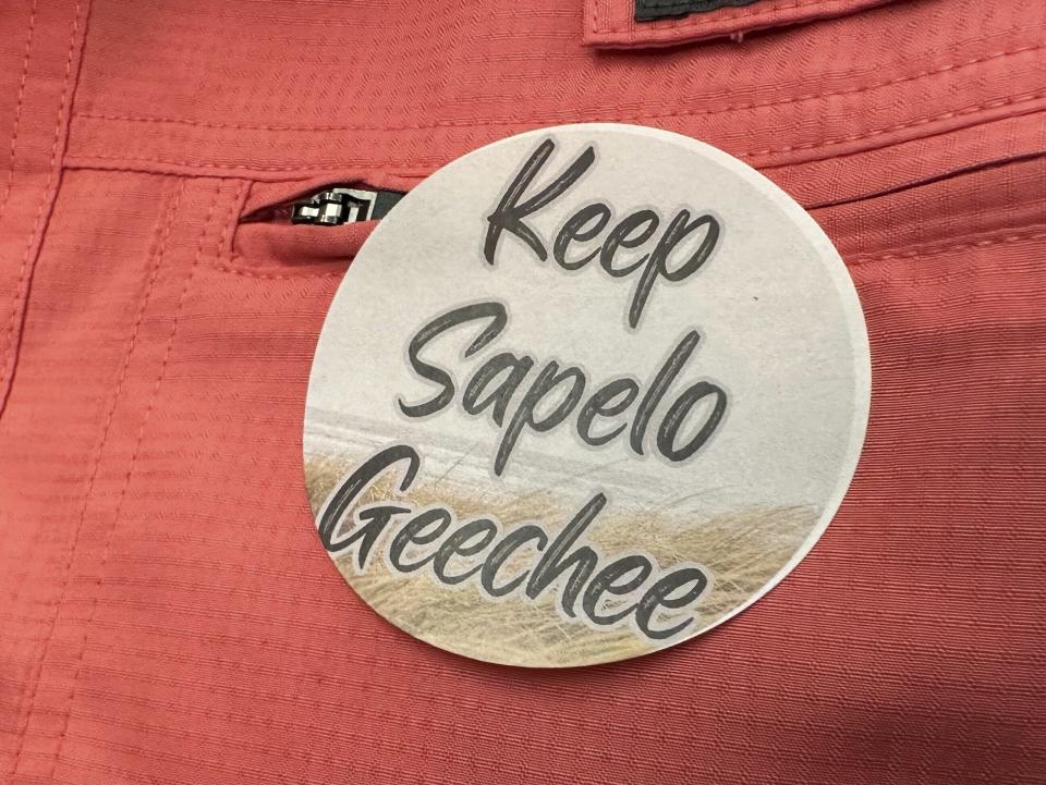 A sticker saying "Keep Sapelo Geechee" is worn on the shirt of George Grovner, a resident of the Hogg Hummock community on Sapelo Island, during a meeting of McIntosh County commissioners Tuesday, Sept. 12, 2023, in Darien, Ga. Commissioners voted to double the maximum size of homes allowed in the tiny community of people known as Gullah-Geechee, who are descended from slaves who worked coastal plantations. Residents say they fear the zoning change will raise their property values and taxes, potentially forcing them to sell their land. (AP Photo/Ross Bynum)