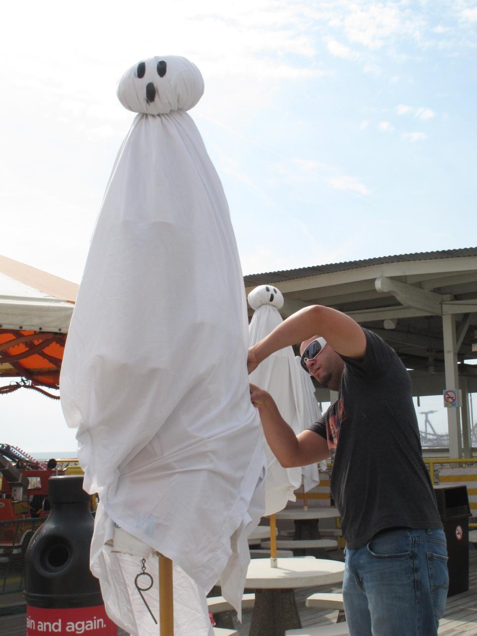 A ghost on the Wildwood N.J. boardwalk seems startled as Morey's Piers employee Jamil Dorta works on him Thursday Sept. 27, 2012. The boardwalk is adapting some of its summertime rides to a Halloween theme to try to extend the tourist season as long as possible. (AP Photo/Wayne Parry)