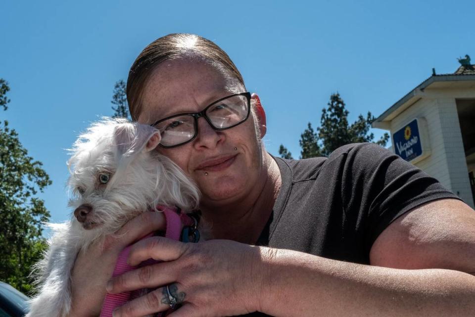 Project Roomkey participant Amber Box-Matson, 37, gets teary-eyed with her dog Aphrodite outside the Vagabond Inn motel in Sacramento on Wednesday, May 17, 2023. With the program at the motel ending, she said she called many of the numbers on a list of potential housing options provided by county officials. She said there were no openings.