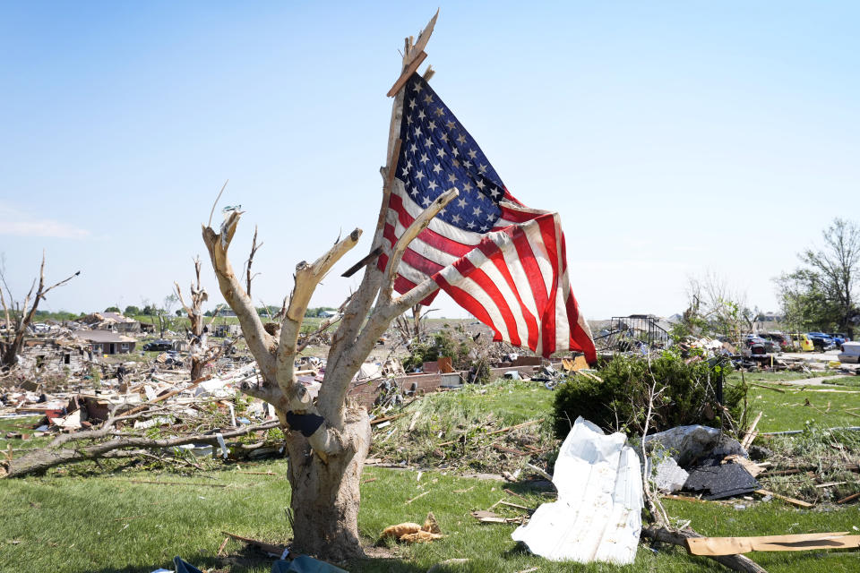 A flag hangs in a tree near tornado damaged homes, Wednesday, May 22, 2024, in Greenfield, Iowa. (AP Photo/Charlie Neibergall)