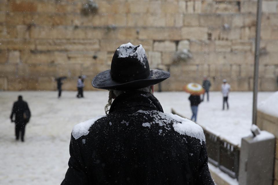 A man holding an umbrella prays at the Western Wall in Jerusalem's Old City during a snowstorm