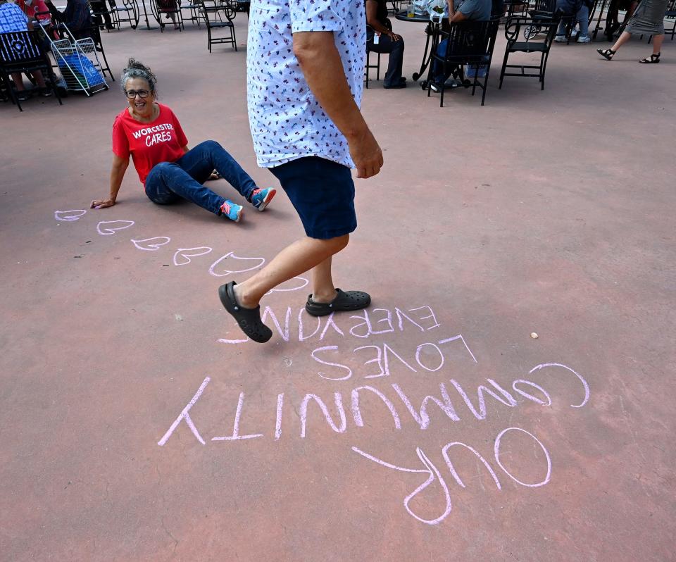 Lila Fain of Hamden, Conn., sits while working on one of the chalk messages drawn throughout the Worcester Common Oval during Thursday's Out To Lunch Festival and Farmers Market. Fain's daughter, Yaffa Fain, works for the event's producer Worcester Cultural Coalition.