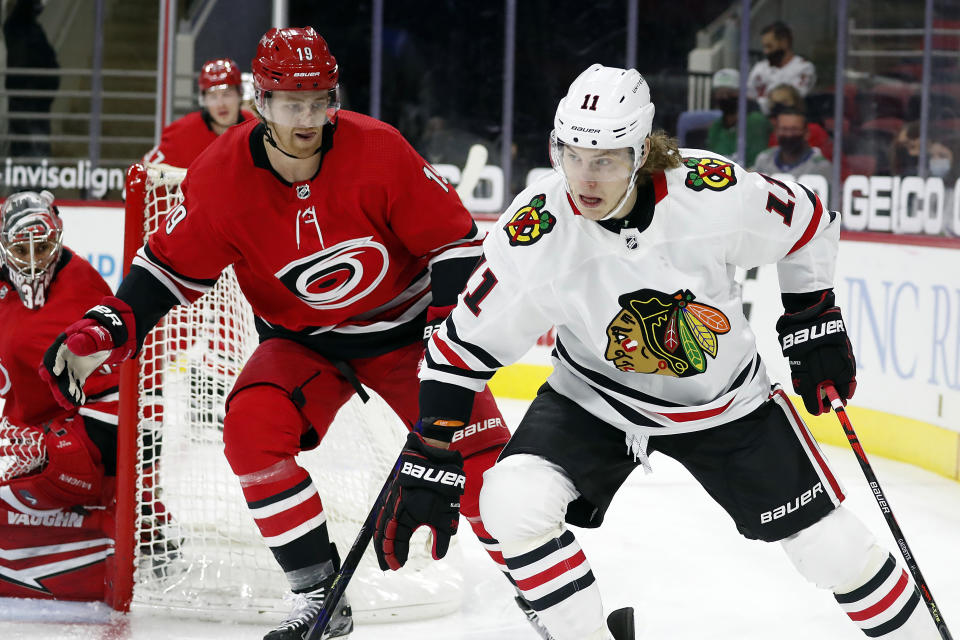 Chicago Blackhawks' Adam Gaudette (11) drives the puck around Carolina Hurricanes' Dougie Hamilton (19) during the first period of an NHL hockey game in Raleigh, N.C., Thursday, May 6, 2021. (AP Photo/Karl B DeBlaker)