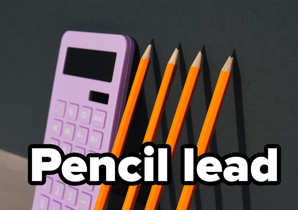 A calculator and four pencils arranged in a straight line on a flat surface