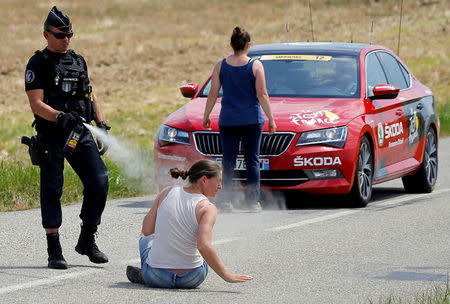 A police officer pepper sprays a protester as another protester stands in front of the race director's car during stage 16. REUTERS/Stephane Mahe