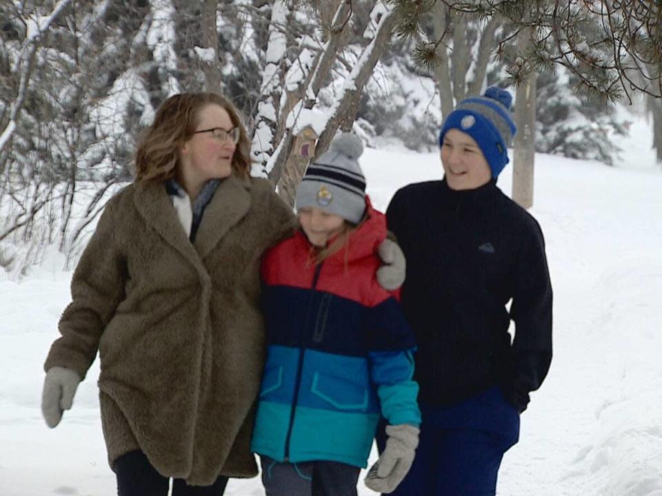 Edmonton parent Jane Purvis (left) and her sons Archie Shandro, 11 (centre), and William Shandro, 13 (right) are debating whether the kids should return to classes in person next week. Cases of the Omicron variant of COVID-19 are soaring in Alberta. Archie is in Grade 5 at Westglen school and William is in Grade 8 at Westminster Junior High. (Craig Ryan/CBC - image credit)