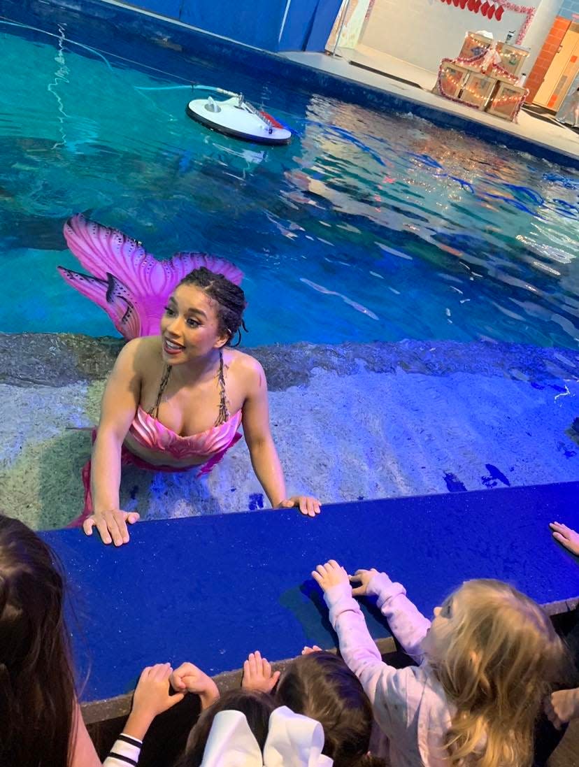 Imari Stout talks to children as she swims in a stingray touch pool. Stout is a professional mermaid performer with Wands and Wishes Mermaids. She performs under the stage name Mermaid Naia.