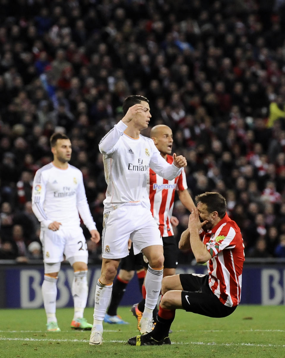 Real Madrid's Cristiano Ronaldo of Portugal, center, gestures after a foul against Athletic Bilbao's Carlos Gurpegi, right, during their Spanish League soccer match against Athletic Bilbao, at San Mames stadium in Bilbao, Spain, Sunday, Feb. 2, 2014. (AP Photo/Alvaro Barrientos)