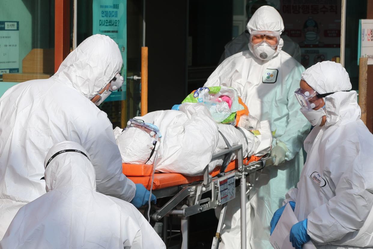 Medical workers wearing protective gear transfer a suspected coronavirus patient to another hospital from Daenam Hospital: YONHAP/AFP via Getty Images