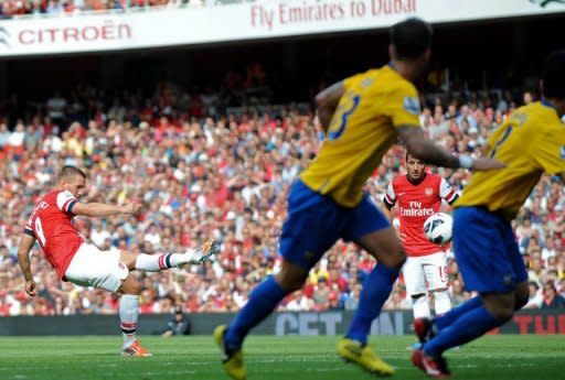 Arsenal's striker Lukas Podolski (L) scores during their English Premier League football match against Southampton at The Emirates Stadium in north London. Arsenal thrashed bottom of the table Southampton 6-1