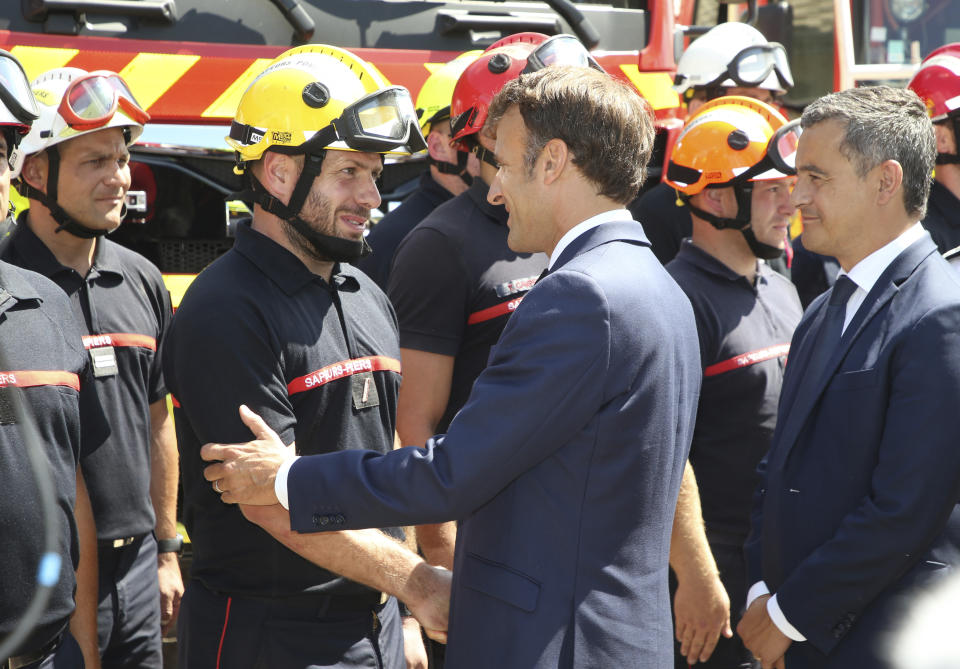 French President Emmanuel Macron, center, meets firefighters at field command post in La Test-de-Buch, near Arcachon, southwestern France, Wednesday, July 20, 2022, while French Interior Minister Gerald Darmanin looks on. In the Gironde region of southwest France, two massive fires feeding on tinder-dry pine forests also have forced tens of thousands of people to flee homes and summer vacation spots since they broke out July 12. (AP Photo/Bob Edme, Pool)