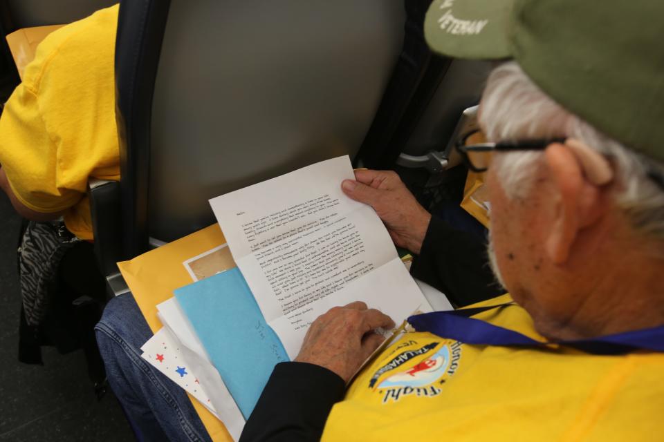 A veteran opens his letters on the return flight, April 27, 2024.