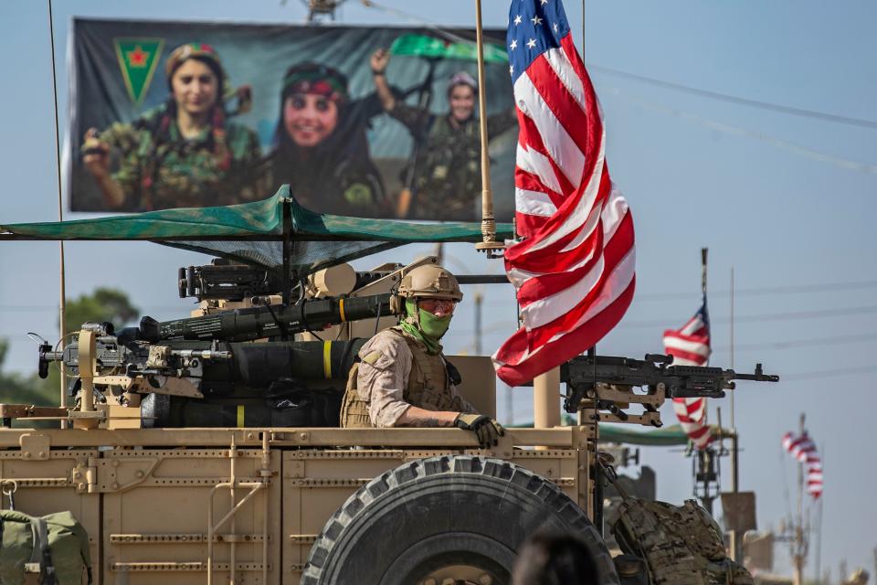 TOPSHOT - A US armoured vehicle drives past a billboard for the Syrian Kurdish Women's Protection Units (YPJ), during a patrol of the Syrian northeastern town of Qahtaniyah at the border with Turkey, on October 31, 2019. - US forces accompanied by Kurdish fighters of the Syrian Democratic Forces (SDF) patrolled part of Syria's border with Turkey, in the first such move since Washington withdrew troops from the area earlier this month, an AFP correspondent reported. (Photo by Delil SOULEIMAN / AFP) (Photo by DELIL SOULEIMAN/AFP via Getty Images)