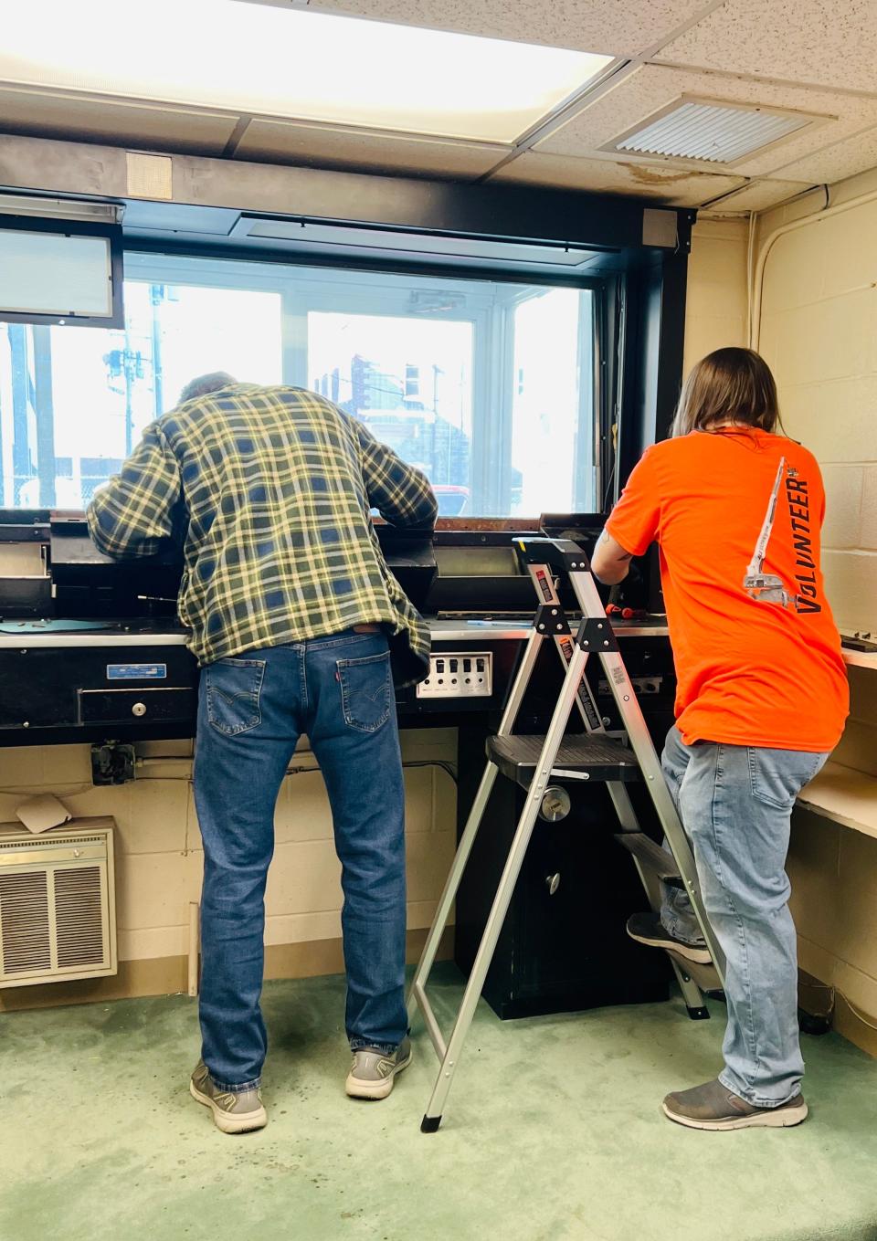 Volunteers form JLG Industries ponder needed repairs to a drive-through apparatus for use by United Way of Washington County.