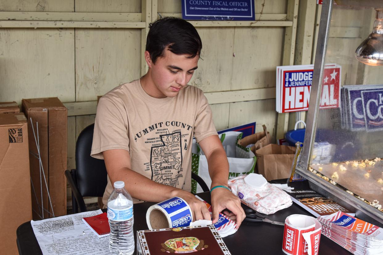 Max Graham, a first-time voter in this year's election, places campaign stickers for Kevin Coughlin, the Republican Ohio nominee for U.S. Senate, on bags of popcorn to be given away at the Summit County Republican Party's at the Summit County Fair July 25 in Tallmadge.