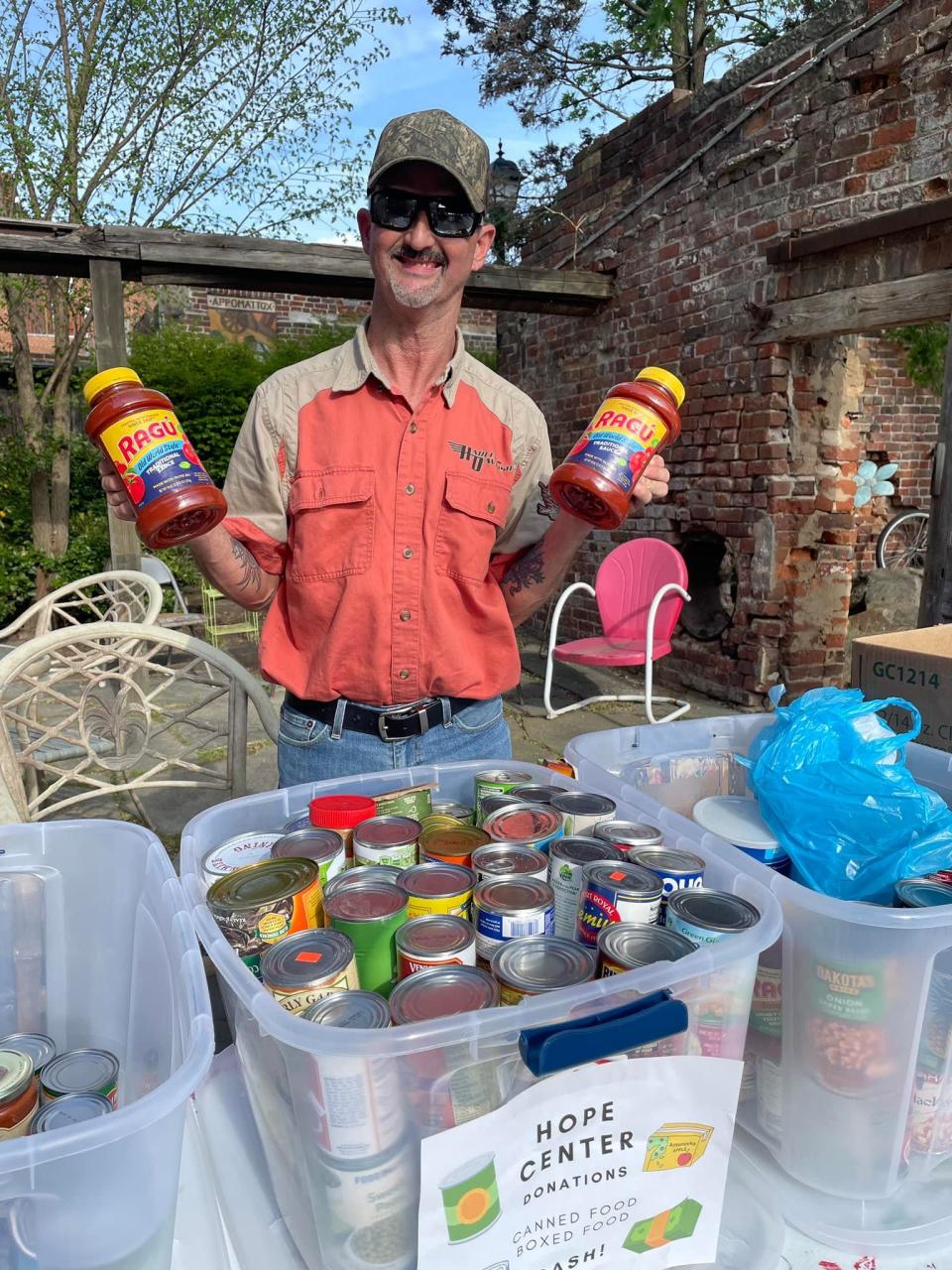 Volunteer Barry Edmonds collects food items for The Hope Center food pantry at "Eggs and Kegs" community musical event held at The Iron Works in Old Towne Petersburg on April 16, 2022.