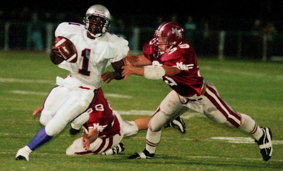 Father Ryan High quarterback Jonathan Wilkes (1) narrowly escapes from MBA defender Clark Lea (35) at the end of the first quarter on Oct. 9, 1998.