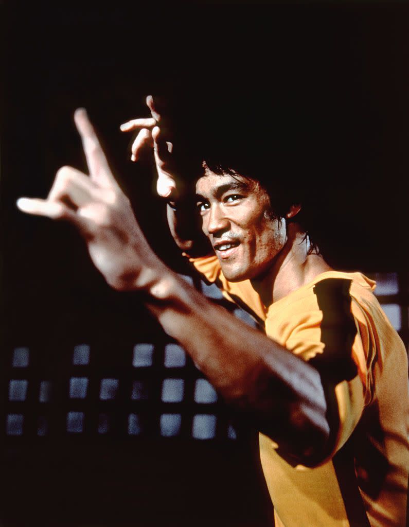 bruce lee wearing a yellow jumpsuit and making a kung fu posture