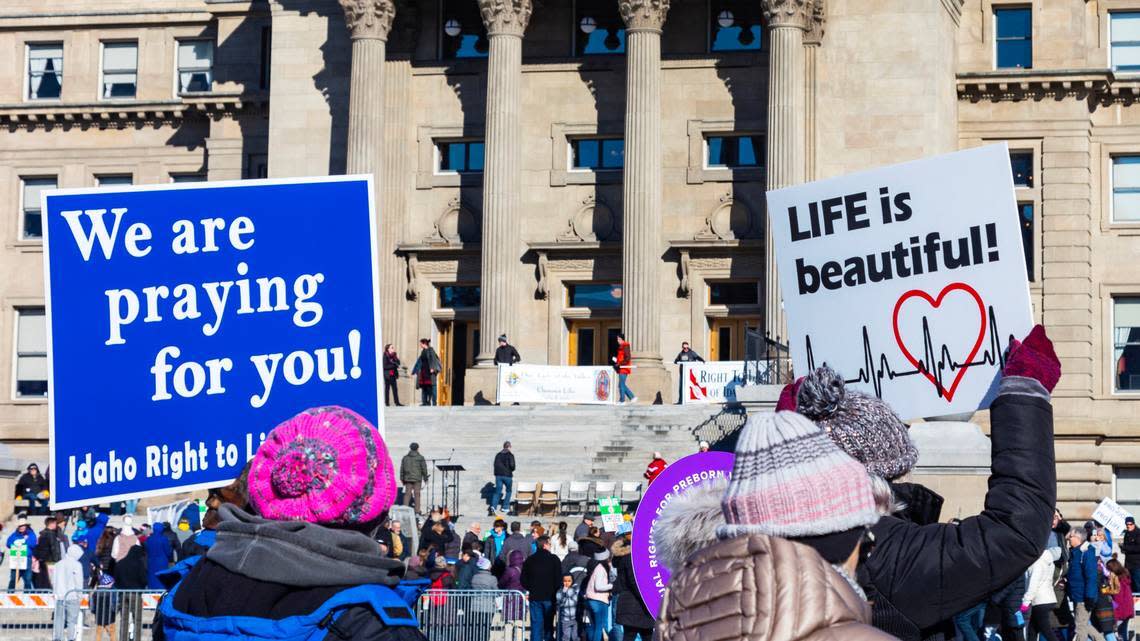 Anti-abortion demonstrators at the Idaho Capitol carry signs reading: We are praying for you.