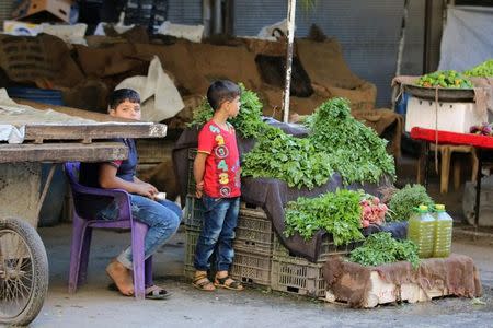 Boys stand near a vegetable stand inside a market in the rebel-held al-Shaar neighbourhood of Aleppo, Syria, September 17, 2016. Picture taken September 17, 2016. REUTERS/Abdalrhman Ismail