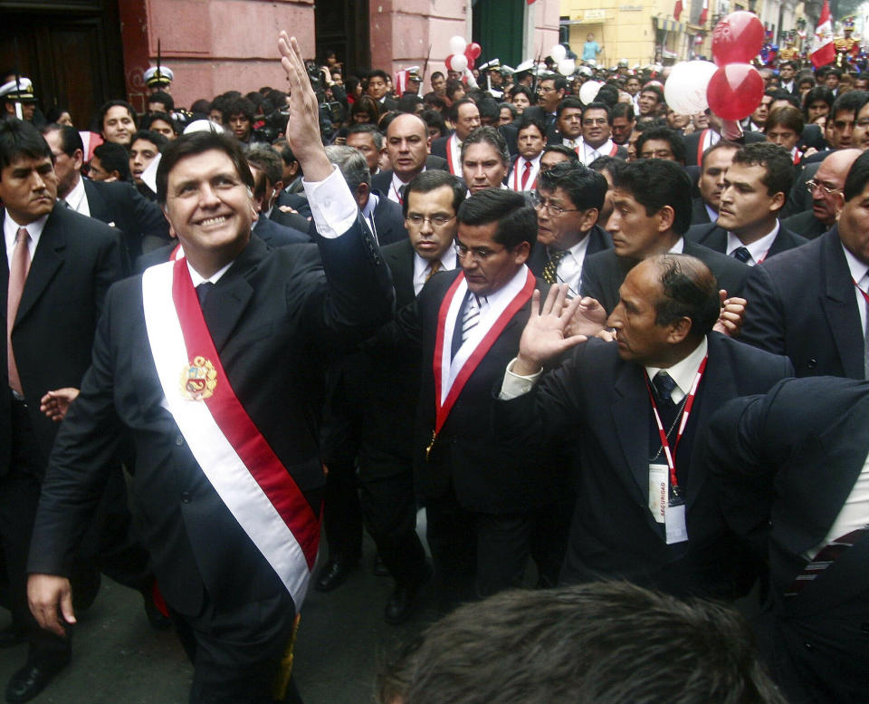 FILE - In this July 28, 2006 file photo, Peruvian President Alan García waves to a crowd after his swearing-in ceremony while he walks through the streets of Lima, Peru. Current President Martinez Vizcarra said Garcia, the 69-year-old former head of state died Wednesday, April 17, 2019, after undergoing emergency surgery in Lima. Garcia shot himself in the head early Wednesday as police came to detain him in connection with a corruption probe. (AP Photo/Ernesto Benavides, File)