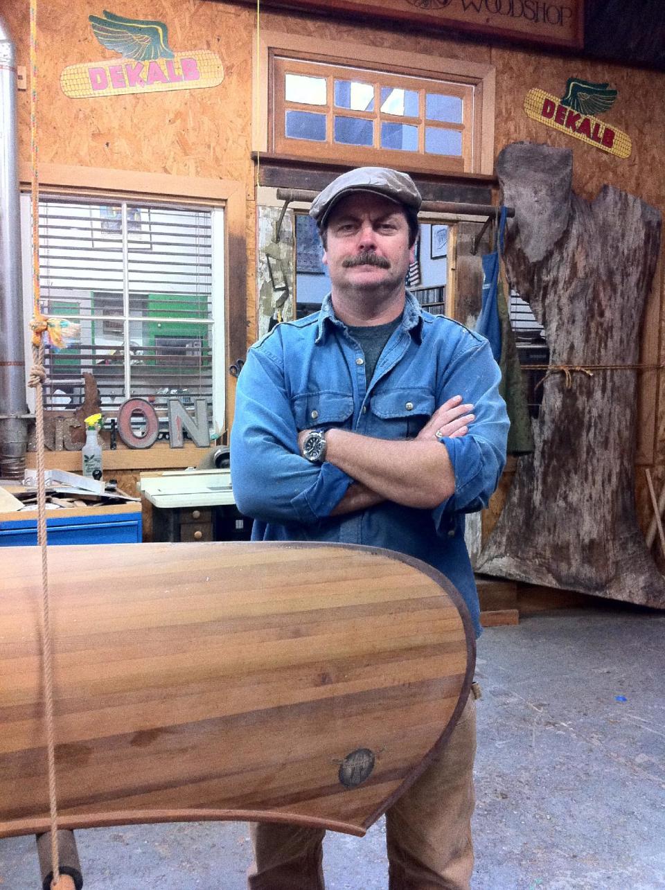 In this February 2012 image released by Jessica Glazer, Nick Offerman, who plays Ron Swanson on NBC's "Parks & Recreation," stands next to one of two canoes he built as shown in his Woodworking Studio in Los Angeles. Building boats requires a particular kind of commitment. It's complex and expensive. It can take months or years. And it can be addictive, working out in the garage, sawdust clinging to your clothes, making mistakes and finding the solutions yourself. (AP Photo/Jessica Glazer)