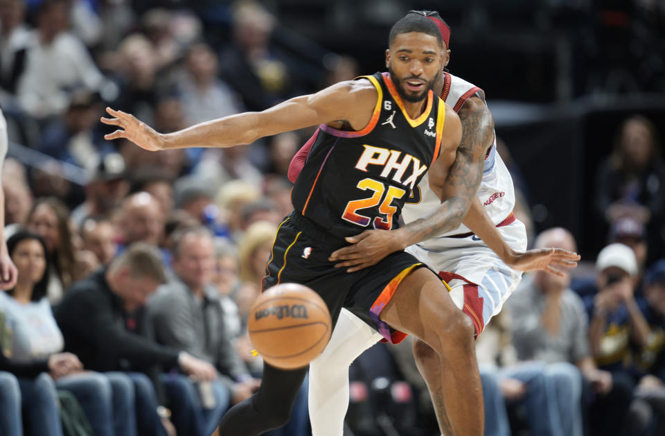 Phoenix Suns forward Mikal Bridges, front, pursues a loose ball with Denver Nuggets guard Kentavious Caldwell-Pope in the first half of an NBA basketball game Wednesday, Jan. 11, 2023, in Denver. (AP Photo/David Zalubowski)