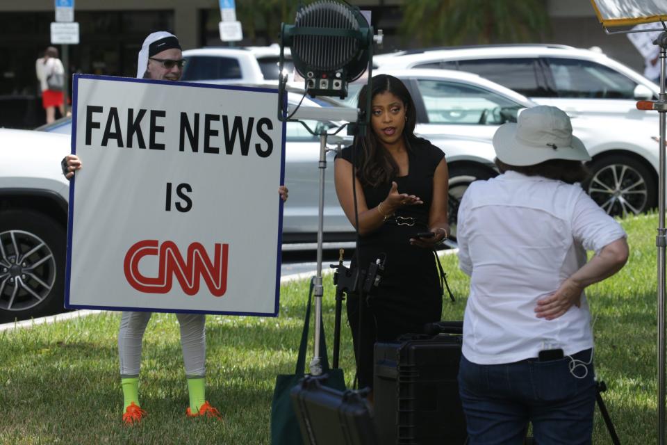 Jim Whelan of West Palm Beach holds a "fake news" sign behind a TV news crew outside the federal courthouse in West Palm Beach, on September 1, 2022.