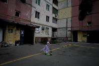 A girl rides a scooter near destroyed buildings during attacks in Irpin outskirts Kyiv, Ukraine, Thursday, June 2, 2022. (AP Photo/Natacha Pisarenko)
