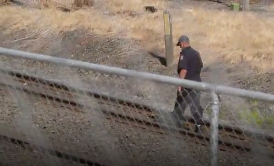 A police officer studies train tracks at Hamilton train station in Frankton, New Zealand where a woman and baby died.