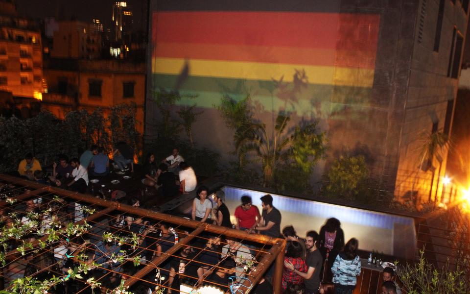 A view from the rooftop gathering with an eight-stripe massive rainbow flag projected on the building facade in the frame for Beirut Pride on May 16, 2017. - Credit: Noureddine Tabbara, courtesy of Beirut Pride