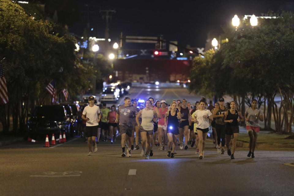 Runners make their way down Main Street in Tupelo, Miss. as they hold their "Liza's Lights" run early Friday morning, Spet. 9, 2022, in Tupelo Miss., to remember Eliza Fletcher, who was abducted and murdered while she was running in the early morning hours in Memphis, Tenn. (Thomas Wells/The Northeast Mississippi Daily Journal via AP)