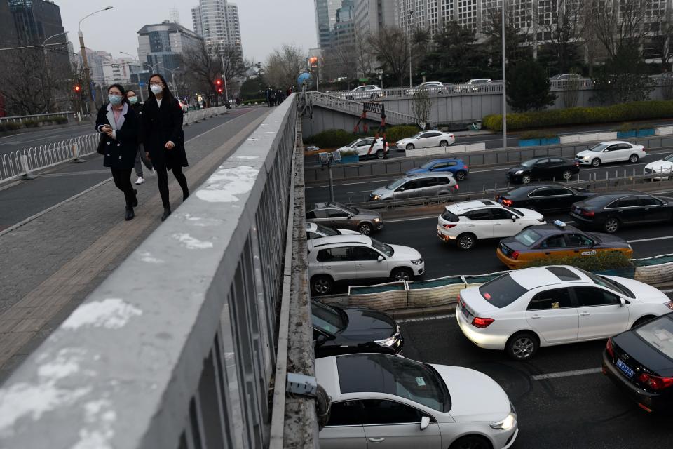 Varias personas cruzan por un puente sobre una autopista repleta de coches en Pekín. La normalidad va volviendo poco a poco a China, epicentro del brote de coronavirus. (Foto: Greg Baker / AFP / Getty Images).