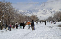People walk on a snow-covered road in Quetta, capital of Pakistan's southwestern Baluchistan province, Monday, Jan. 13, 2020. Severe winter weather has struck parts of Afghanistan and Pakistan with heavy snowfall, rains and flash floods that left more than 54 dead, officials said Monday as authorities struggled to clear and reopen highways and evacuate people to safer places. (AP Photo/Arshad Butt)