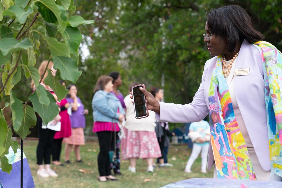 Topeka USD 501 superintendent Tiffany Anderson shows former classroom para Sasha Camacho at Shaner Elementary, via Facetime, the yellow marigold tree planted in Zoey Felix's honor during a ceremony Thursday evening outside the school.