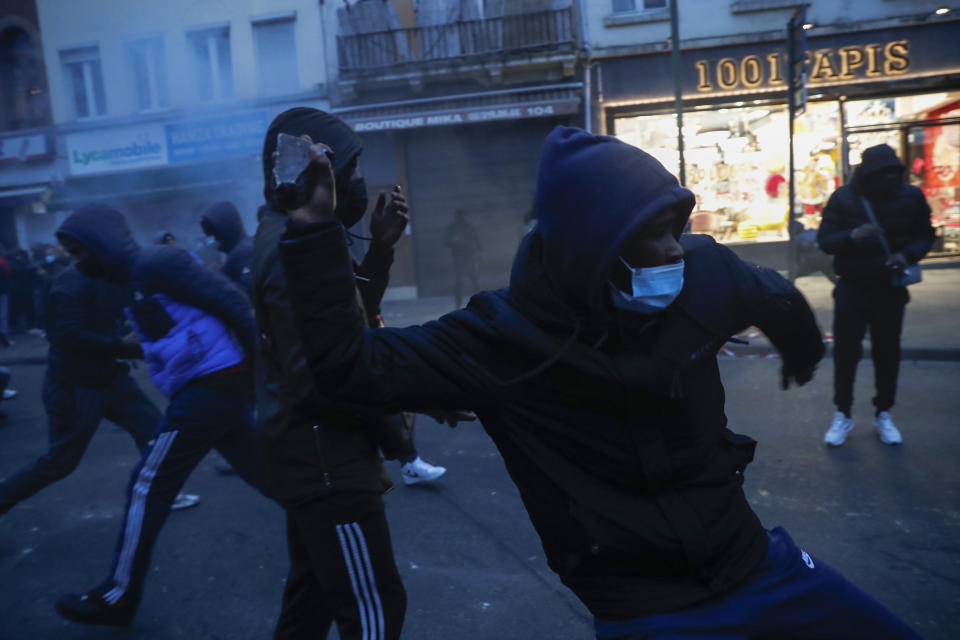 A protestor throws stones toward a police office in the Belgium capital, Brussels, Wednesday, Jan. 13, 2021, at the end of a protest asking for authorities to shed light on the circumstances surrounding the death of a 23-year-old Black man who was detained by police last week in Brussels. The demonstration in downtown Brussels was largely peaceful but was marred by incidents sparked by rioters who threw projectiles at police forces and set fires before it was dispersed. (AP Photo/Francisco Seco)