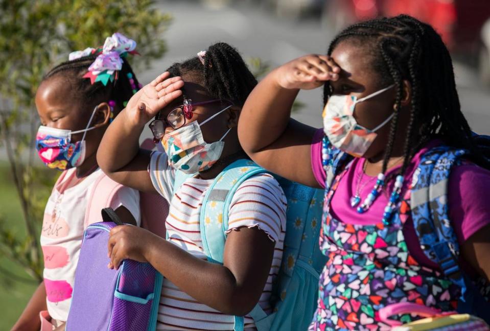 The Robbins sisters, Jessyca, 6, left, Julianna, 6, middle, and Journi, 9, right, pose for pictures for their parents before going into Conn Elementary School in Raleigh, N.C. on the first day of school, Monday, Aug. 23, 2021.