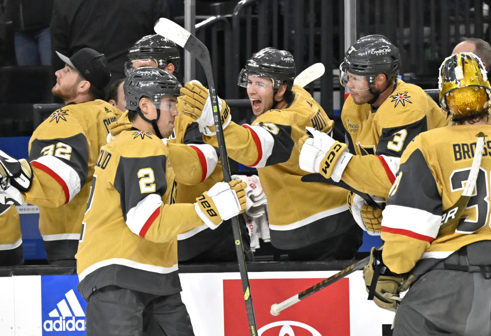 Vegas Golden Knights defenseman Zach Whitecloud (2) celebrates with the defenseman Ben Hutton (17) and the bench after scoring against the Minnesota Wild during the first period of an NHL hockey game Saturday, April 1, 2023, in Las Vegas. (AP Photo/David Becker)