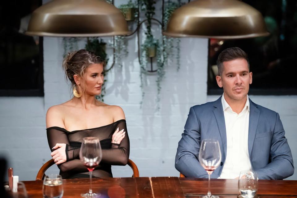 lauren and jono on marred at first sight australia sitting at a dinner table looking tense