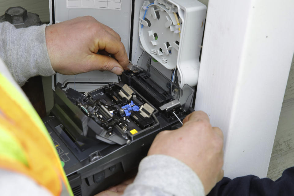 Jason Morisseau, hands only, an installation and maintenance technician with Waitsfield and Champlain Valley Telecom, uses a fusion splicer to install fiber optic cable that is being run to a home, in Concord, Vt., Thursday Feb. 10, 2022. The nationwide need to connect homes and businesses to high-speed broadband services was highlighted by the COVID-19 pandemic and officials say that while there is lots of money available, supply and labor shortages are making the expansion a challenge. (AP Photo/Wilson Ring)