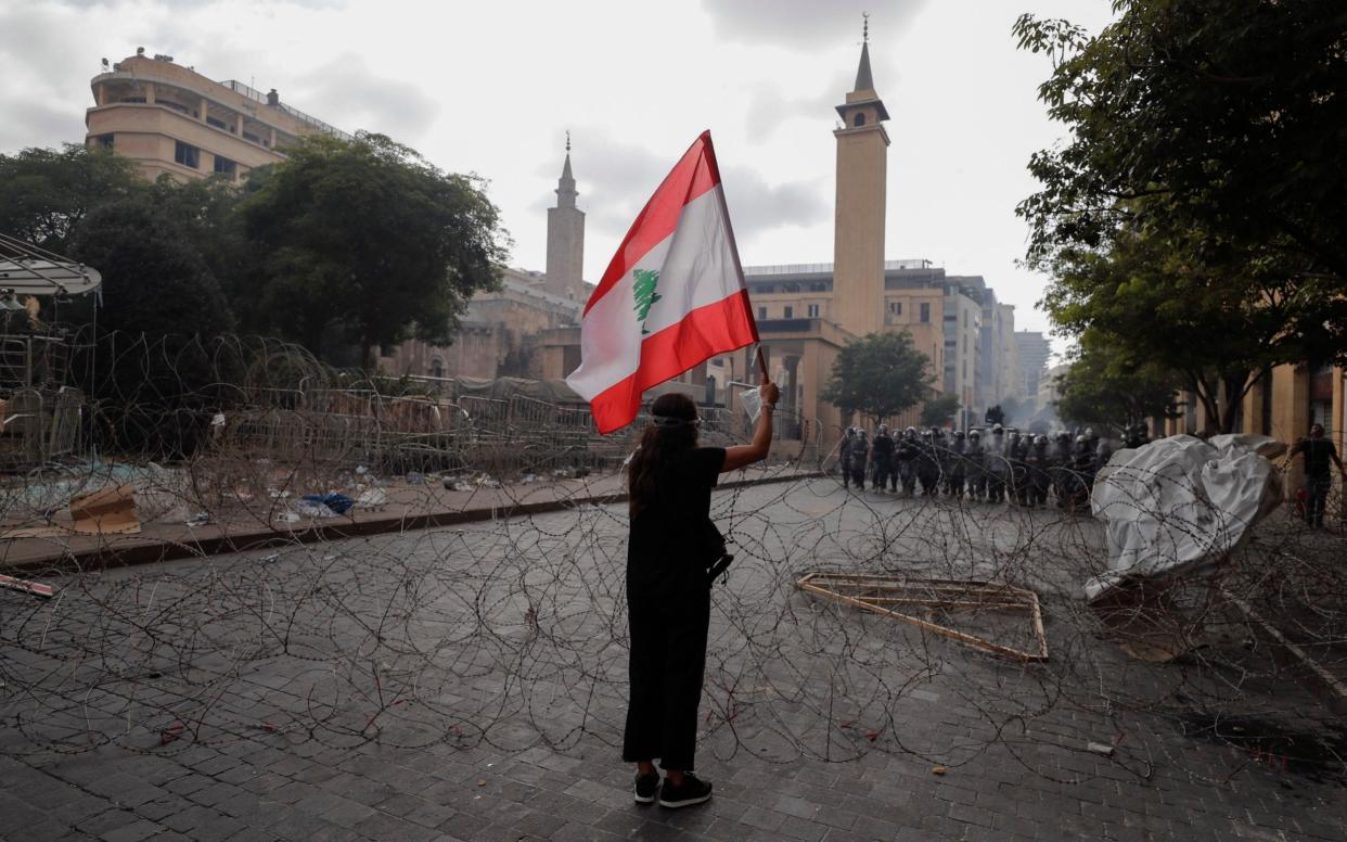 A woman waves the Lebanese flag during a protest against the political elites  - AP