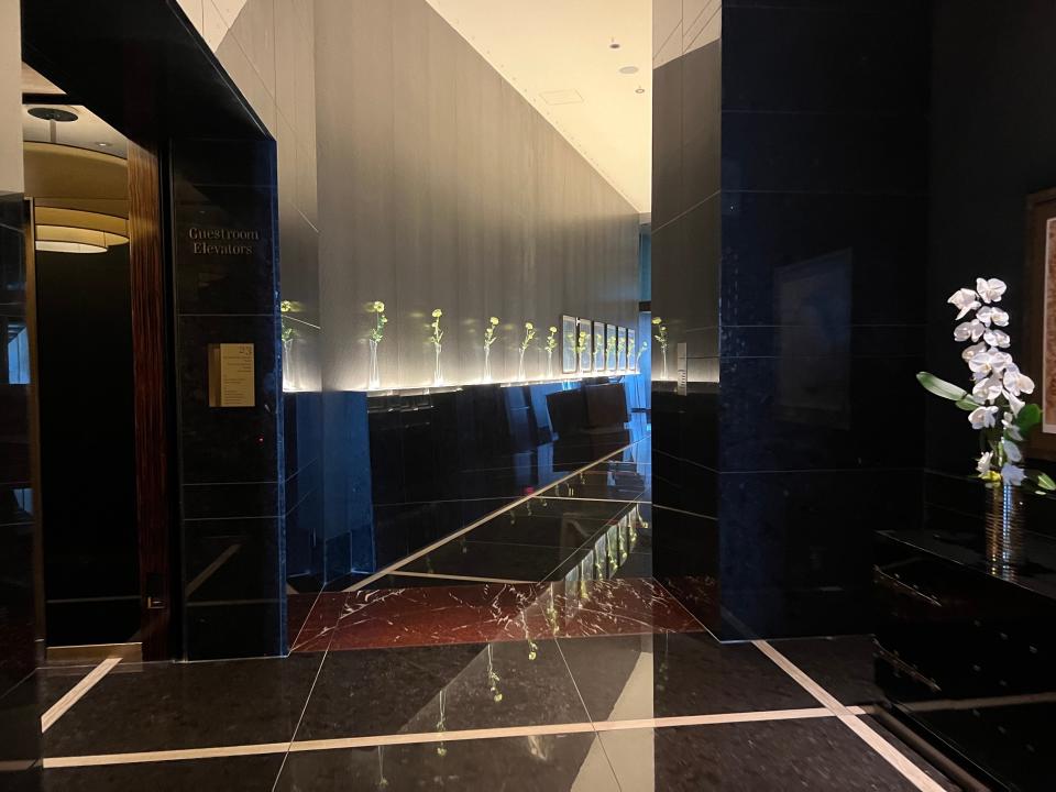 A hallway lined with flowers and black marble walls and floors.