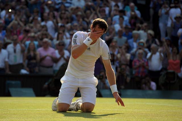 Andy Murray kneels on the court and covers his face with his hand after winning his first Wimbledon title