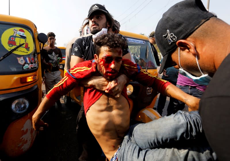Demonstrators carry an injured man during a protest over corruption, lack of jobs, and poor services, in Baghdad