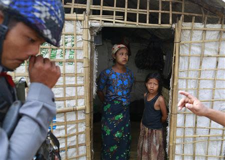 A family stand at the entrance of their temporary shelter as the government embarks on a national census at a Rohingya refugee camp in Sittwe, the capital of Rakhine State April 1, 2014. REUTERS/Soe Zeya Tun